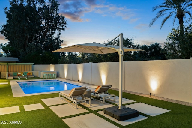 pool at dusk featuring a yard and a patio