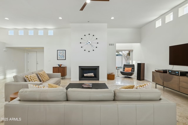 living room featuring ceiling fan and a towering ceiling