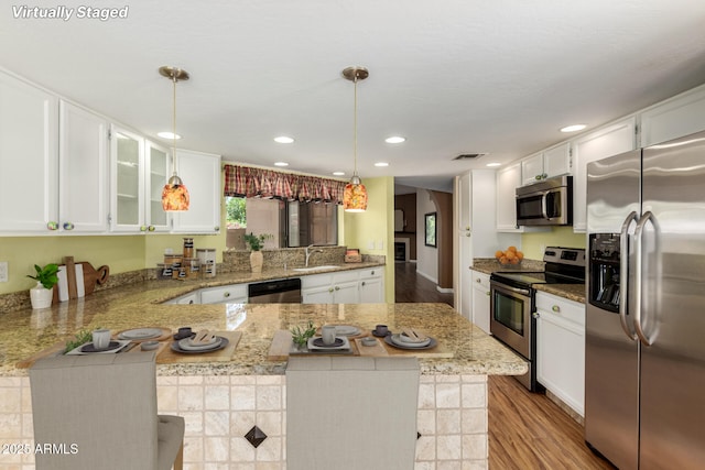 4135 E Altadena Ave, Phoenix, AZ 85028 - kitchen with stainless steel appliances, a peninsula, wood finished floors, white cabinets, and light stone counters