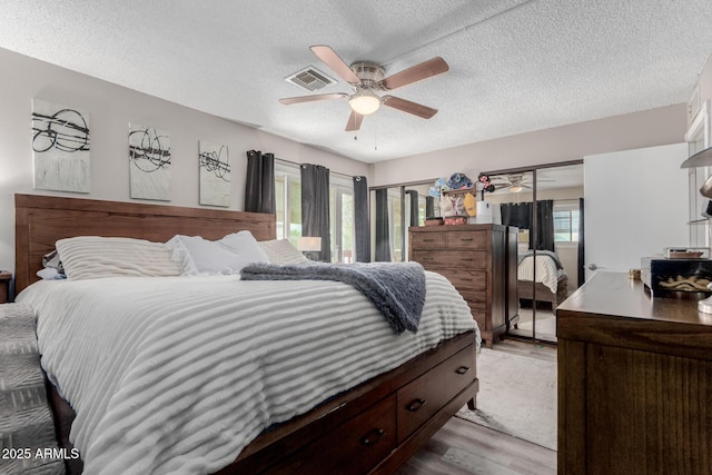 14001 N 34th Dr, Phoenix, AZ 85053 - bedroom with wood finished floors, a textured ceiling, multiple windows, ceiling fan, and multiple closets