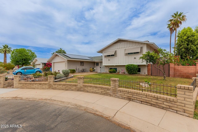 14001 N 34th Dr, Phoenix, AZ 85053 - split level home featuring board and batten siding, solar panels, an attached garage, and driveway