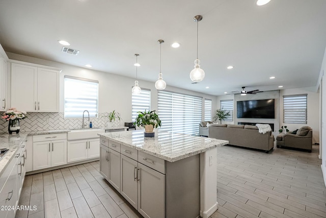 kitchen featuring ceiling fan, pendant lighting, white cabinets, and a healthy amount of sunlight