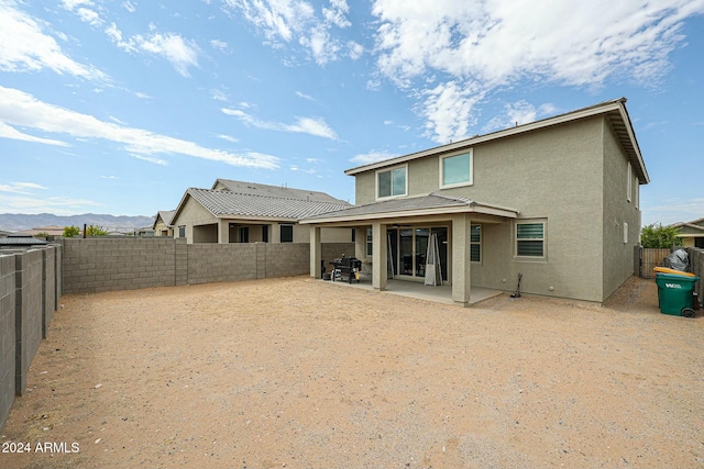 back of property with a mountain view and a patio