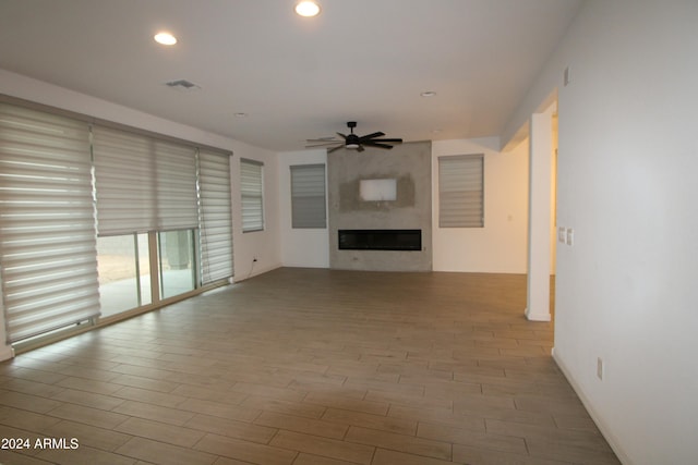 unfurnished living room featuring a fireplace, light hardwood / wood-style flooring, and ceiling fan