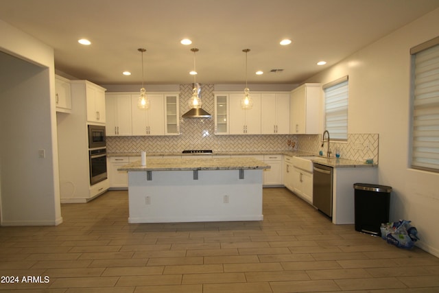 kitchen with appliances with stainless steel finishes, light stone counters, sink, a center island, and white cabinetry