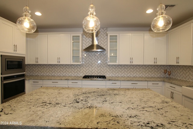 kitchen featuring decorative backsplash, white cabinets, decorative light fixtures, and appliances with stainless steel finishes