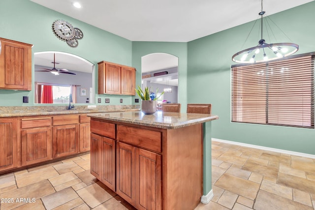 2699 E Claxton Rd, Gilbert, AZ 85297 - kitchen with arched walkways, a ceiling fan, light stone finish flooring, and decorative light fixtures
