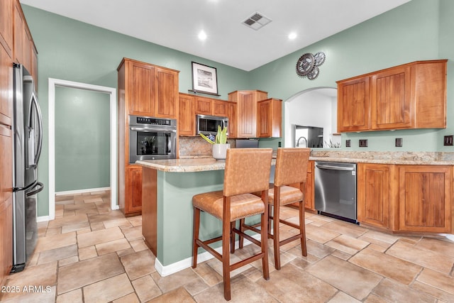 2699 E Claxton Rd, Gilbert, AZ 85297 - kitchen featuring appliances with stainless steel finishes, light stone finish floors, a breakfast bar area, light stone counters, and arched walkways