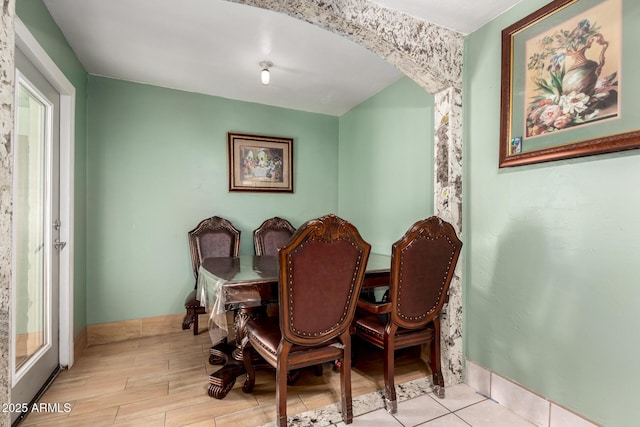 dining room with baseboards, arched walkways, and wood finished floors