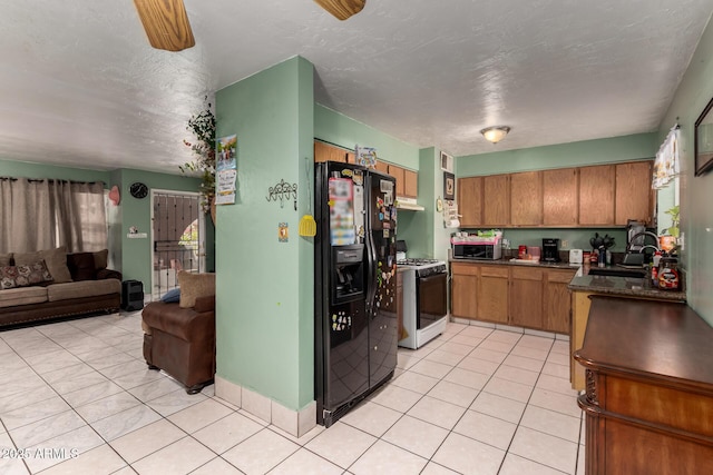 kitchen featuring black fridge with ice dispenser, range with gas stovetop, a sink, stainless steel microwave, and open floor plan