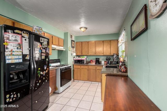 kitchen with black fridge with ice dispenser, gas range, under cabinet range hood, a sink, and brown cabinetry