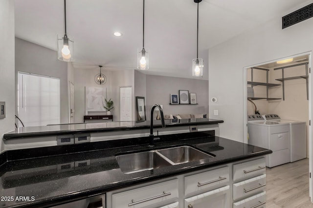 7936 E Wilshire Dr Unit 205, Scottsdale, AZ 85257 - kitchen featuring light wood-type flooring, washing machine and clothes dryer, white cabinetry, dark stone counters, and a sink