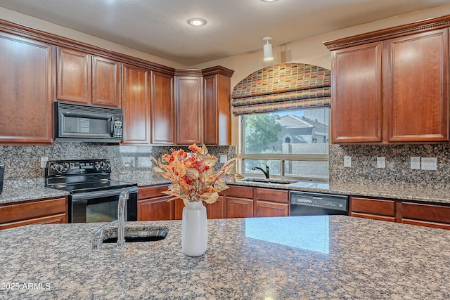 kitchen with dark stone counters, backsplash, sink, and black appliances