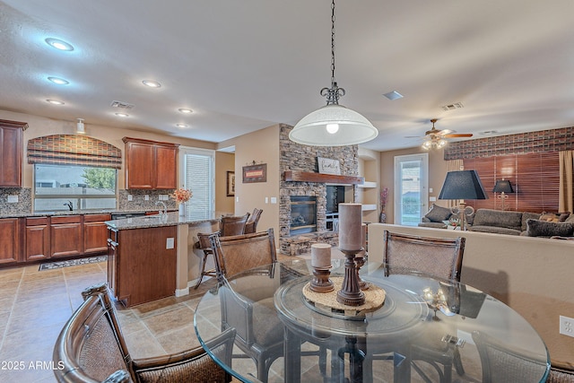 dining room featuring ceiling fan, sink, and a fireplace