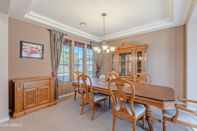 dining area with a tray ceiling, light carpet, and a notable chandelier