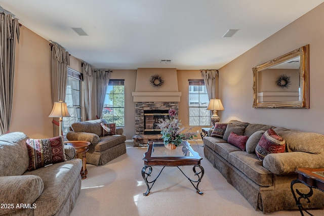 carpeted living room with a stone fireplace