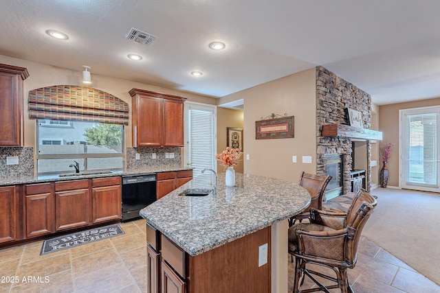 kitchen with a center island, a stone fireplace, sink, black dishwasher, and tasteful backsplash