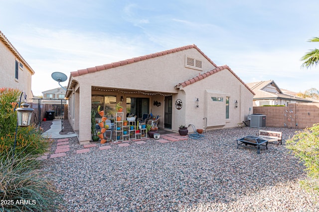 rear view of property featuring central AC unit, fence, a fire pit, and stucco siding