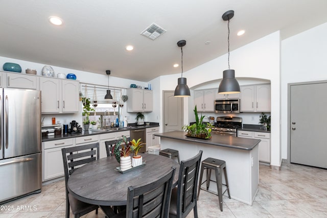 kitchen with stainless steel appliances, dark countertops, and decorative light fixtures