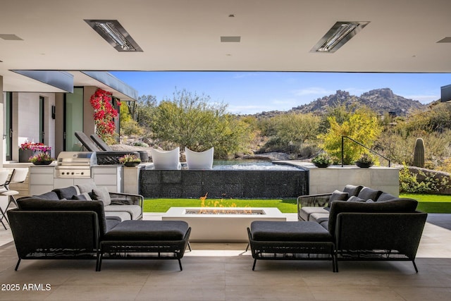 view of patio with a mountain view, an outdoor living space with a fire pit, a grill, and exterior kitchen