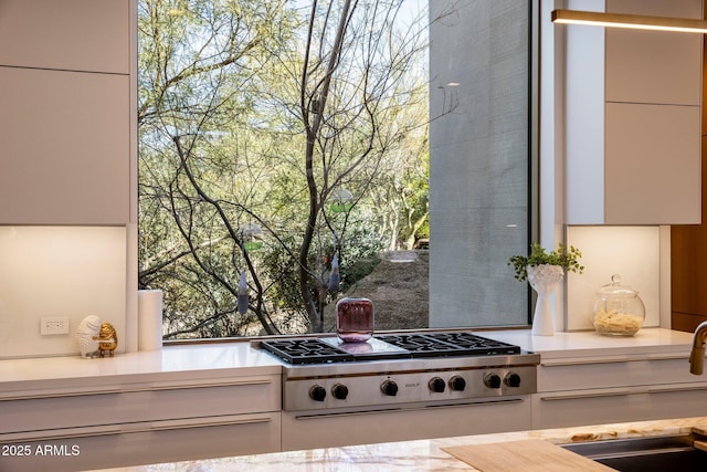 kitchen with stainless steel gas cooktop, sink, and white cabinets