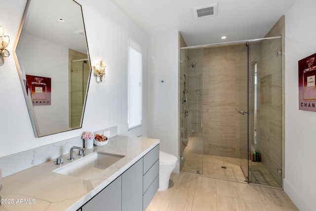 bathroom featuring vanity, a shower with door, and toilet