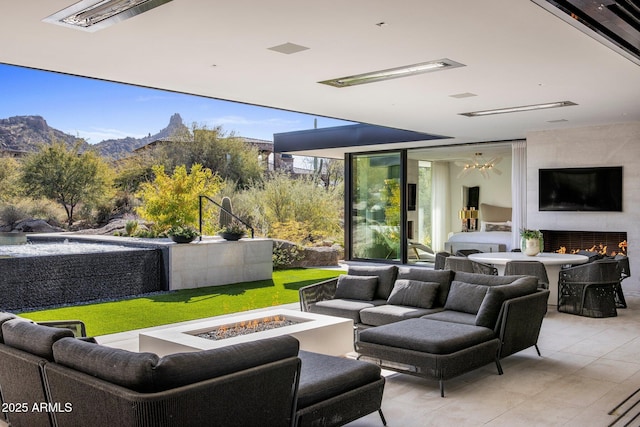 view of patio with a mountain view and an outdoor living space with a fire pit