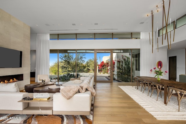 living room featuring a towering ceiling, a fireplace, and light wood-type flooring