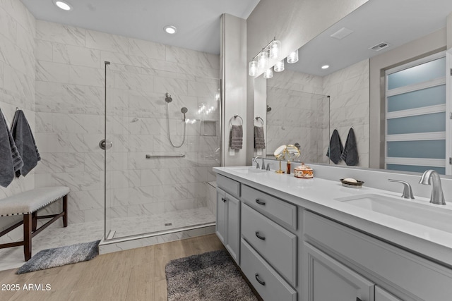 bathroom with hardwood / wood-style floors, vanity, a tile shower, and tile walls