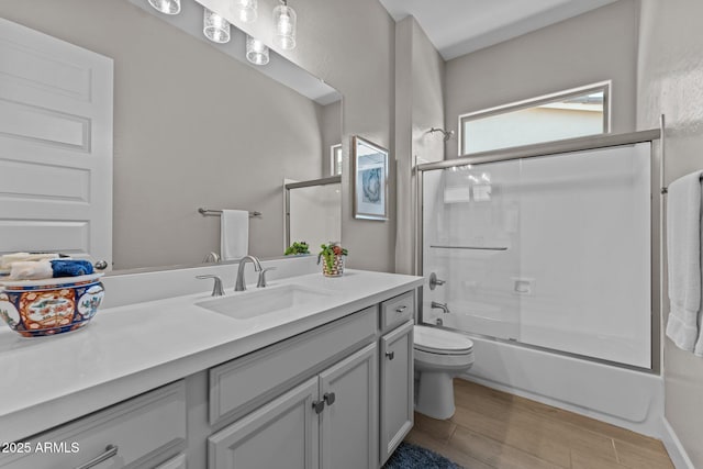 full bathroom featuring vanity, wood-type flooring, toilet, and combined bath / shower with glass door