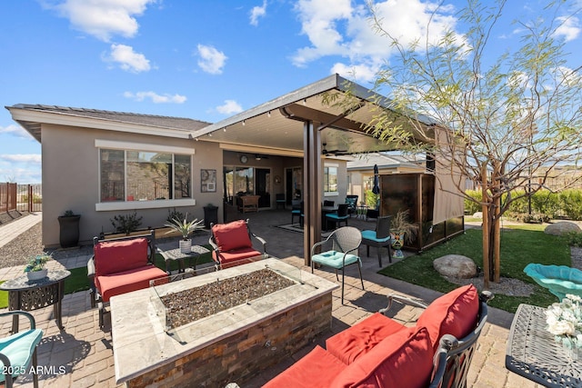 view of patio featuring ceiling fan and an outdoor living space with a fire pit