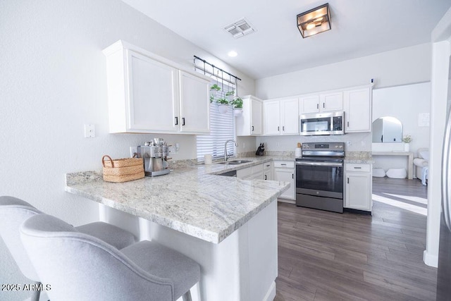 kitchen featuring stainless steel appliances, kitchen peninsula, sink, and white cabinets