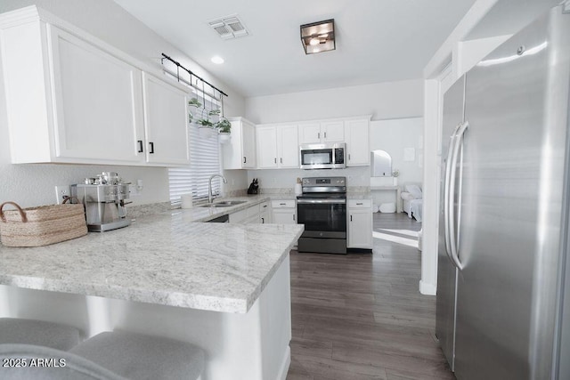 kitchen featuring sink, appliances with stainless steel finishes, dark hardwood / wood-style floors, white cabinets, and kitchen peninsula