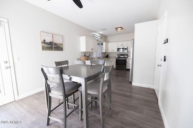 dining space with ceiling fan, sink, and dark hardwood / wood-style flooring