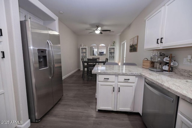 kitchen featuring light stone countertops, stainless steel appliances, kitchen peninsula, and white cabinets