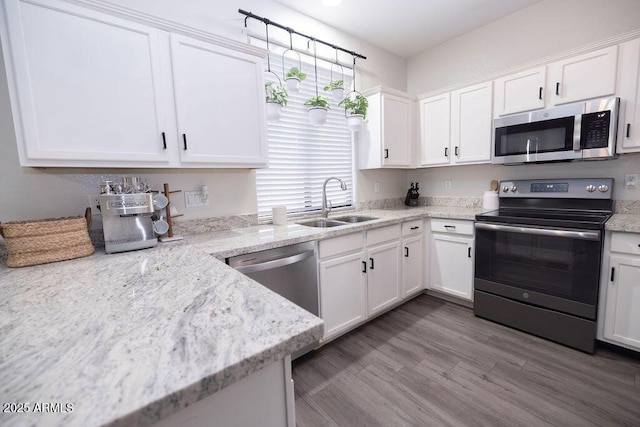 kitchen featuring light stone counters, stainless steel appliances, and white cabinets