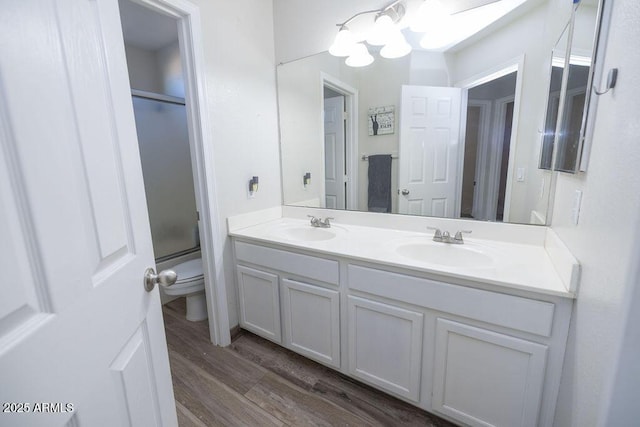 bathroom featuring vanity, toilet, a shower with shower door, and hardwood / wood-style floors