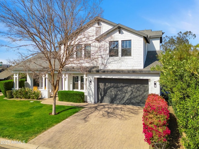 view of front of property with a front lawn, decorative driveway, and an attached garage