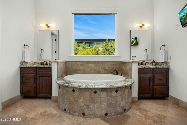 full bath featuring two vanities, a garden tub, and a sink