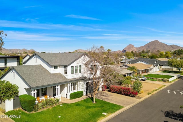 view of front of home with roof with shingles, a porch, concrete driveway, a mountain view, and a residential view