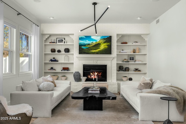 living area featuring a brick fireplace, built in shelves, and visible vents