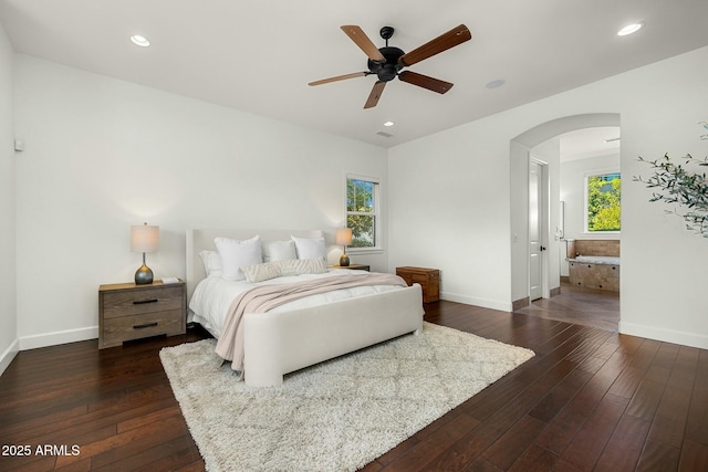 bedroom featuring arched walkways, multiple windows, dark wood-style flooring, and baseboards