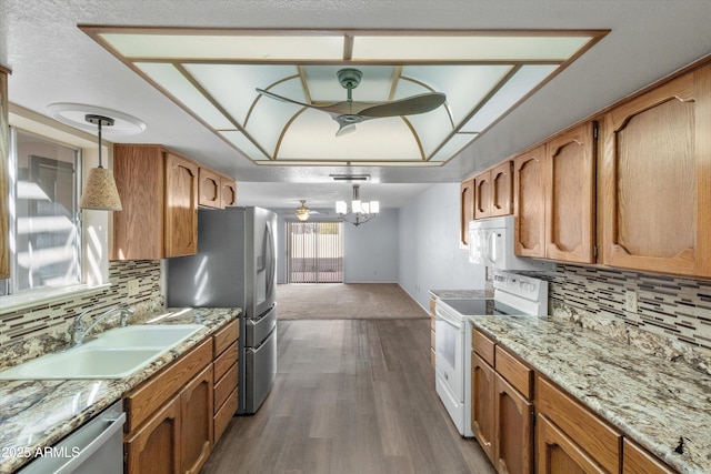 kitchen with appliances with stainless steel finishes, pendant lighting, sink, ceiling fan, and dark wood-type flooring