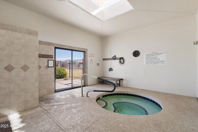 view of swimming pool with a skylight and an indoor hot tub