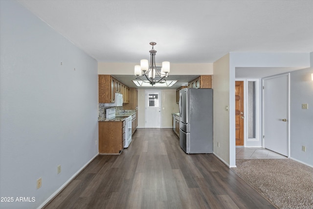 kitchen with dark wood-type flooring, white electric range oven, stainless steel refrigerator, a notable chandelier, and backsplash