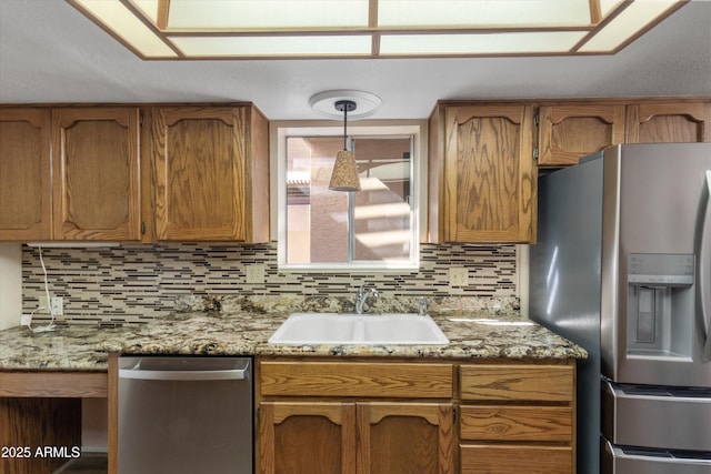 kitchen with pendant lighting, tasteful backsplash, sink, light stone counters, and stainless steel appliances