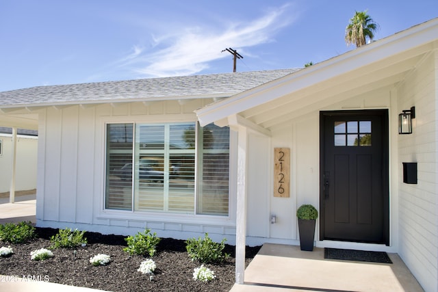 property entrance featuring a shingled roof and board and batten siding