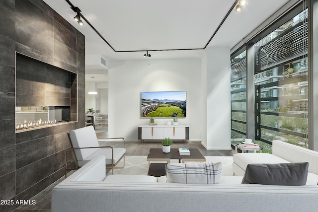 living room with floor to ceiling windows, plenty of natural light, a tile fireplace, and rail lighting