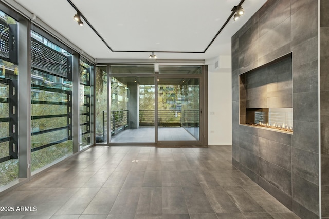 spare room with a wall of windows, rail lighting, and tile patterned flooring