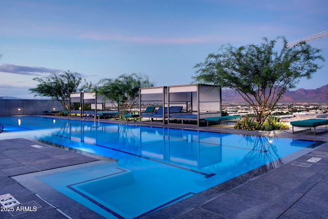 pool at dusk featuring a mountain view